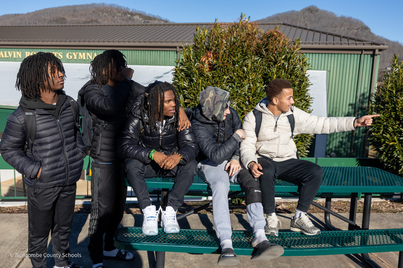 Students watching floats along the parade route. One student is pointing.
