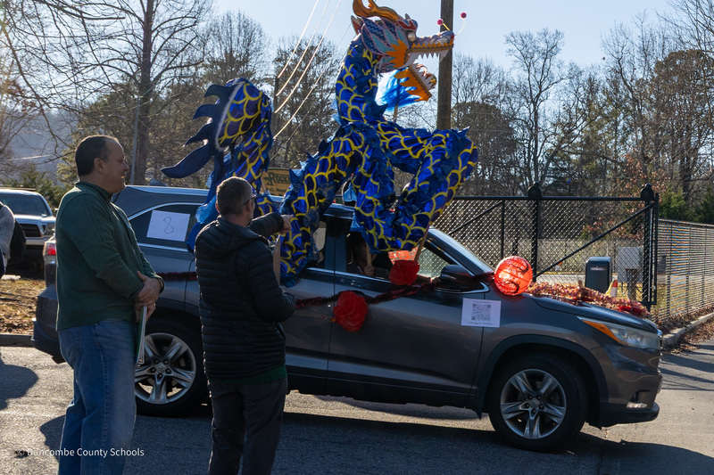 A student drives a vehicle with an inflatable dragon on the roof