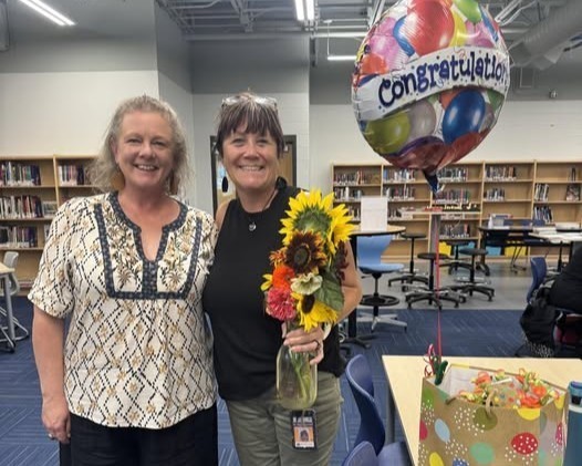 Tonya Gesing holds a bouquet of flowers and a "Congratulations" balloon as she stands in the Community High media center next to principal Cathy Haughney