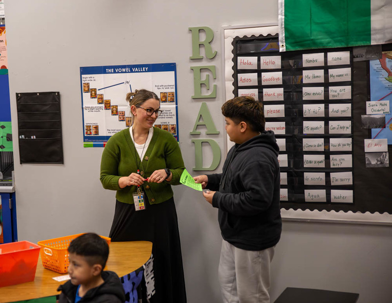 A teacher works with student visitors to a decorated classroom.