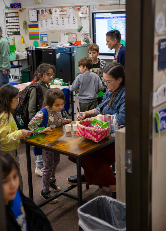 A teacher works with student visitors to a decorated classroom.
