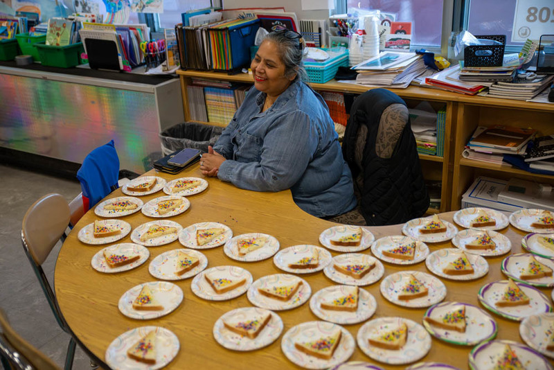 A teacher sits smiling next to prepares snacks.