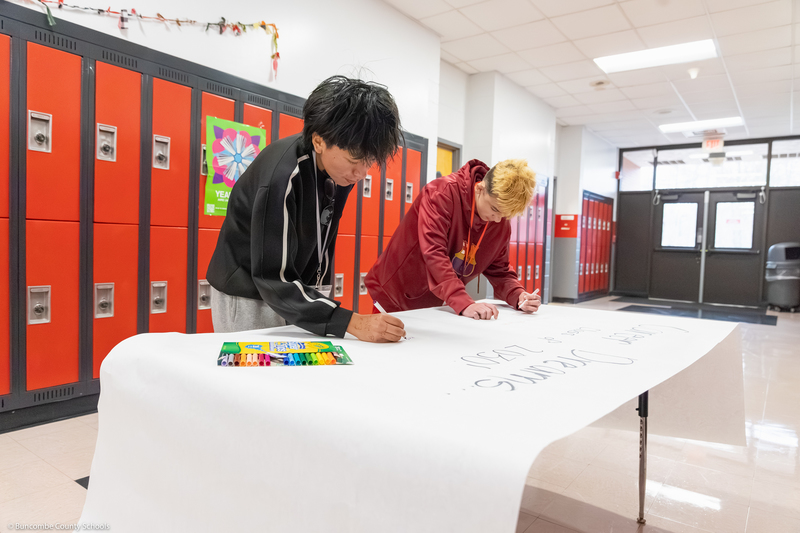 Students write about potential careers on a large sheet of paper.