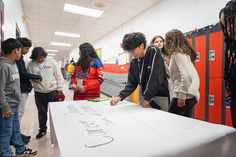 Students write about potential careers on a large sheet of paper.