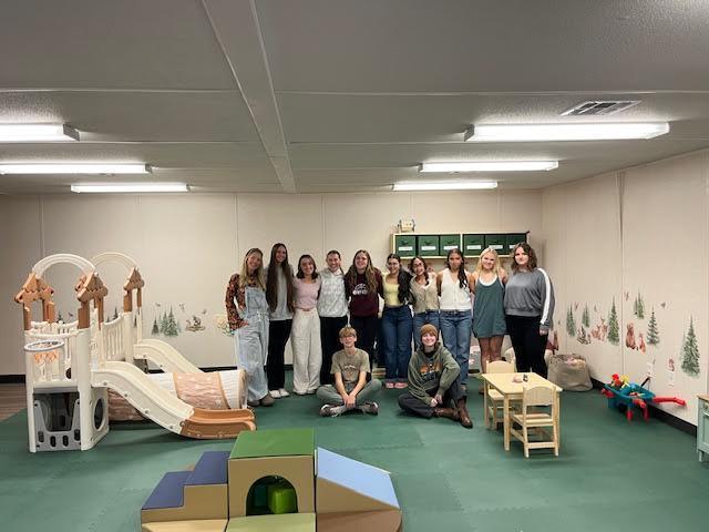 Students gathered around the indoor playroom posing for a group photo. 