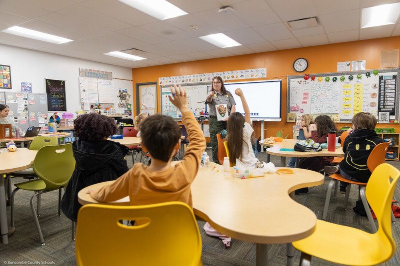 A student raises his hand while a Park Ranger points at him.