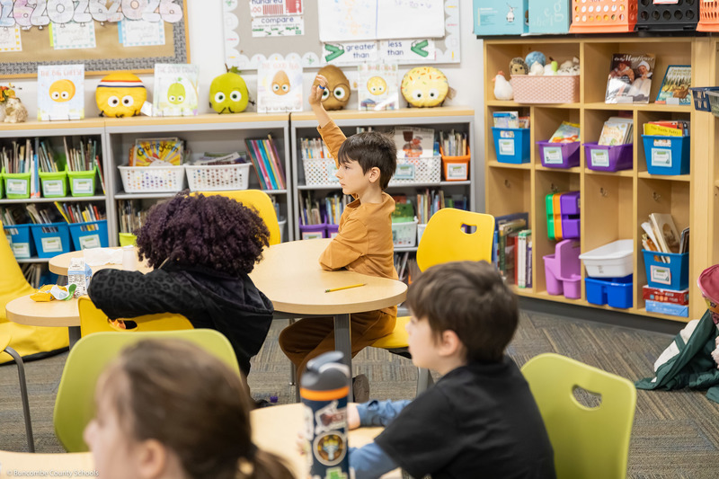 A student raises his hand while sitting.