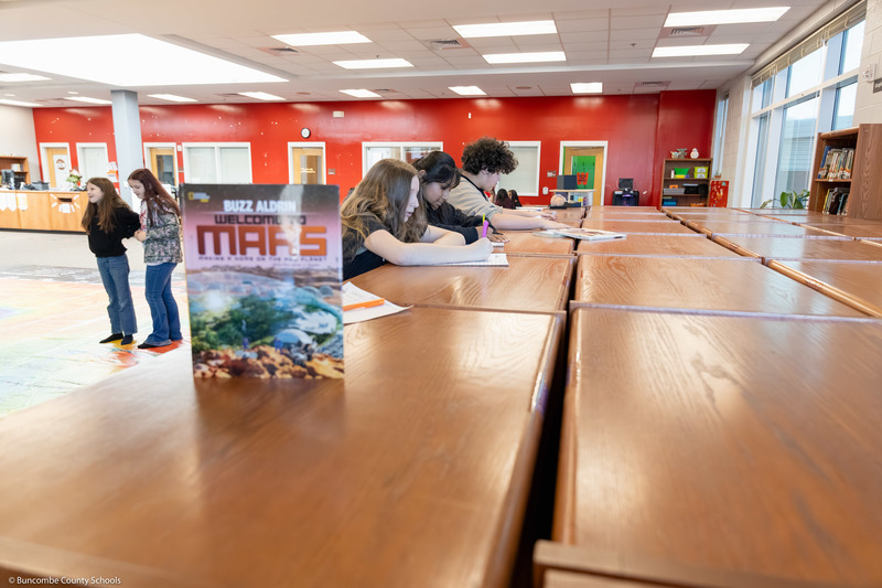 Three students write on worksheets.