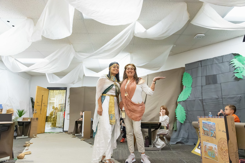Two teachers pose wearing outfits reflecting ancient civilizations.