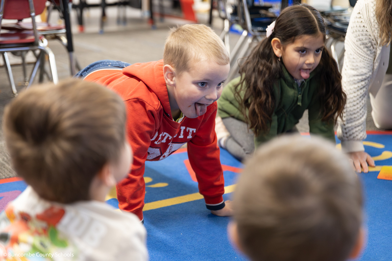 Little boy and girl on their hands and knees pretending to be lions. They both have their tongues stuck out. 