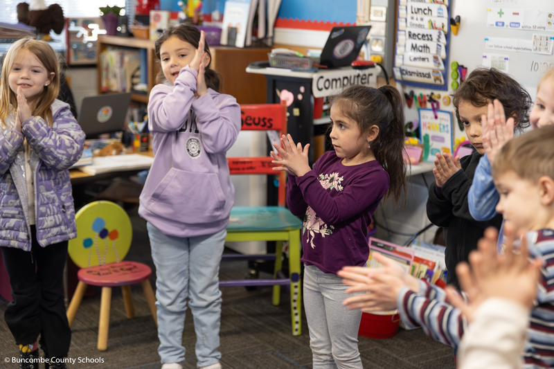 Group of kindergarteners rubbing their hands together as part of a breathing exercise. 