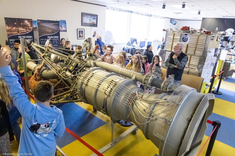 Students gather round part of a rocket booster.