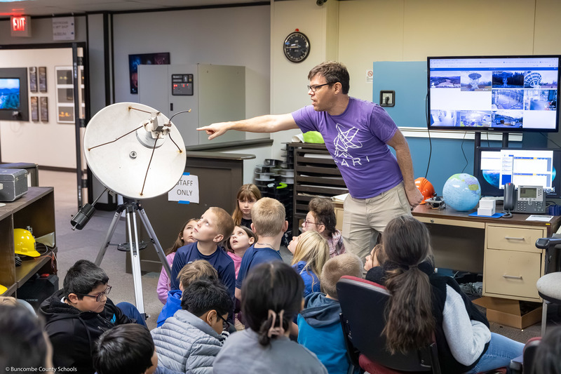 PARI education director Tim Delisle points at a small radio telescope while speaking to the kids.
