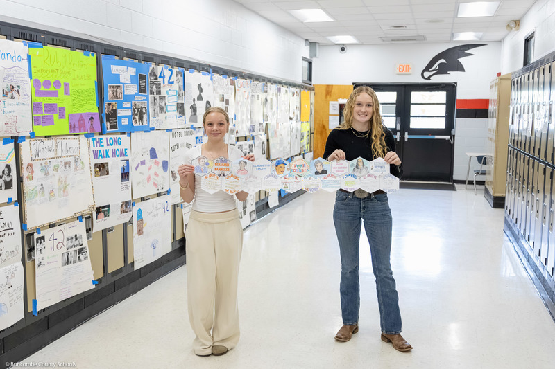 Two students hold part of the quilt in a school hallway.