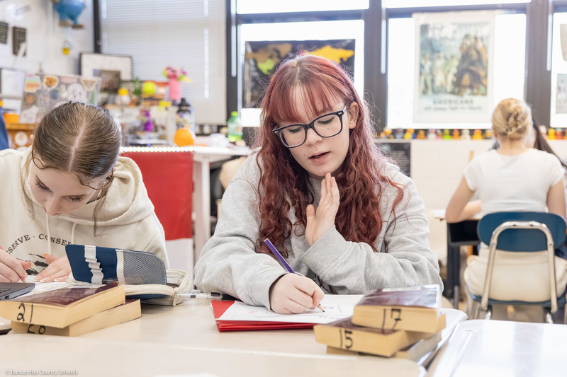 Two students work on part of the quilt inside the classroom.