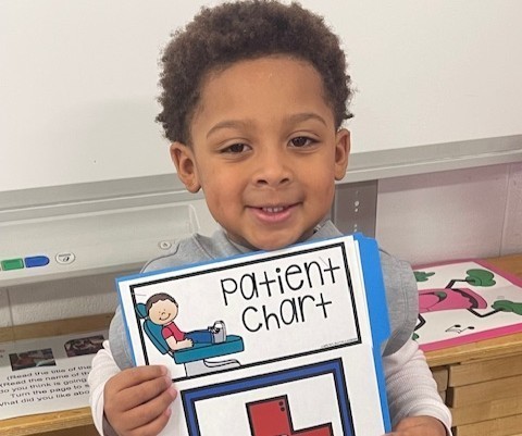 A student holds a pretend dental patient chart