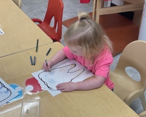 A photo of a student coloring a worksheet of a giant tooth