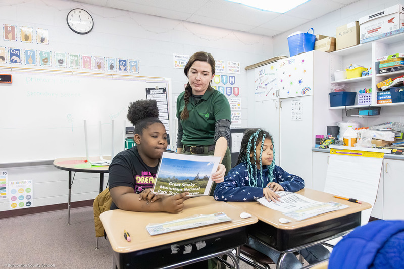 A ranger helps a group of kids with the project.