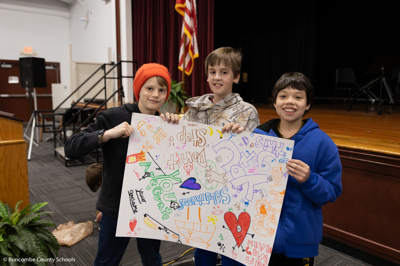 Three students holding up the poster they made.