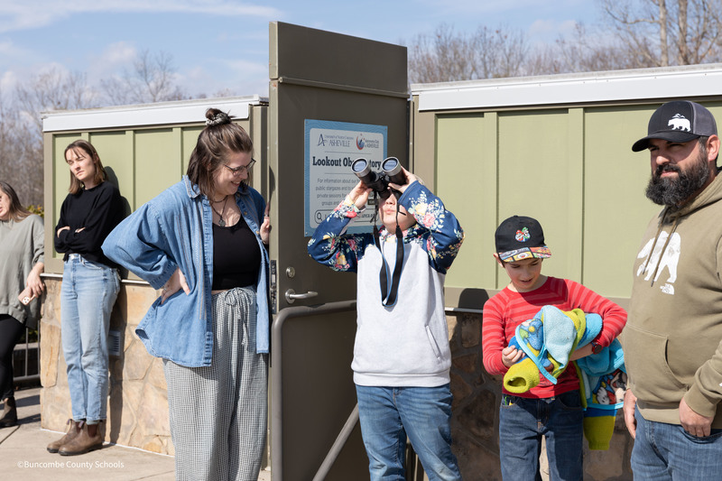 student looking through binoculars