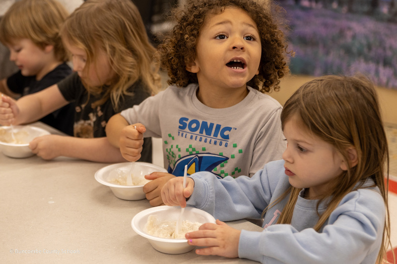Students sit at a table and stir ingreidents in their bowls