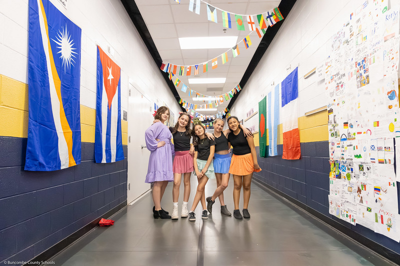 Five students pose in a decorated hallway.