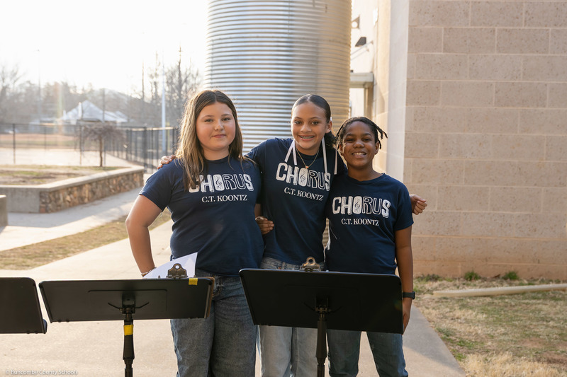 Three chorus students pose outside the school.