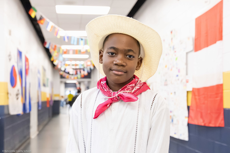 A student in cultural attire poses in the hallway.