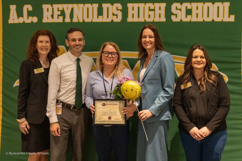Ms. Martin, Principal Ben Alexander, Ms. Walters, Dr. Johnson, and Ms. Houchard pose for a photo in front of a school banner.