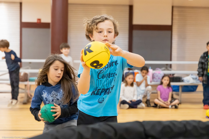 A student shoots a ball into a net.
