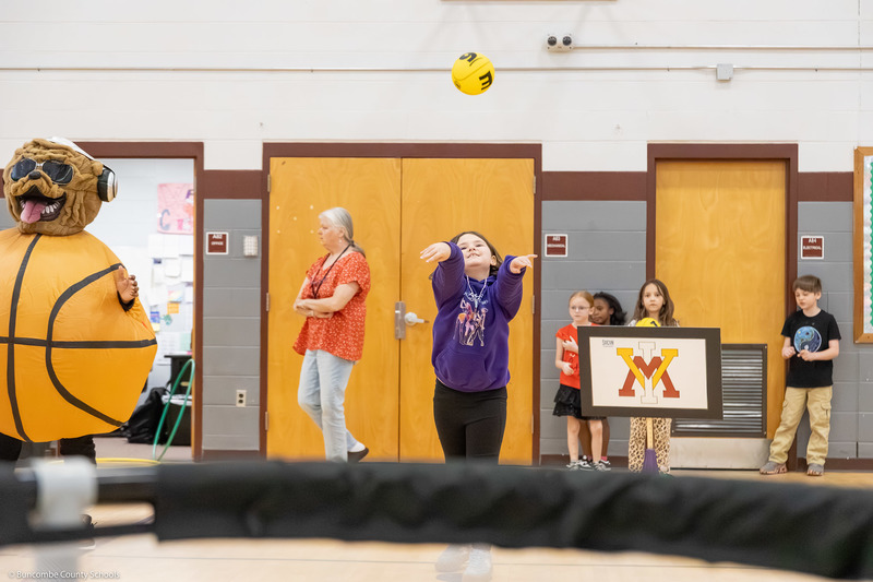 A student shoots a ball into a net.