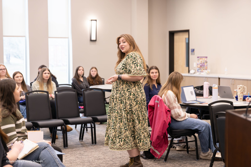 Teacher standing in front of seated students talking