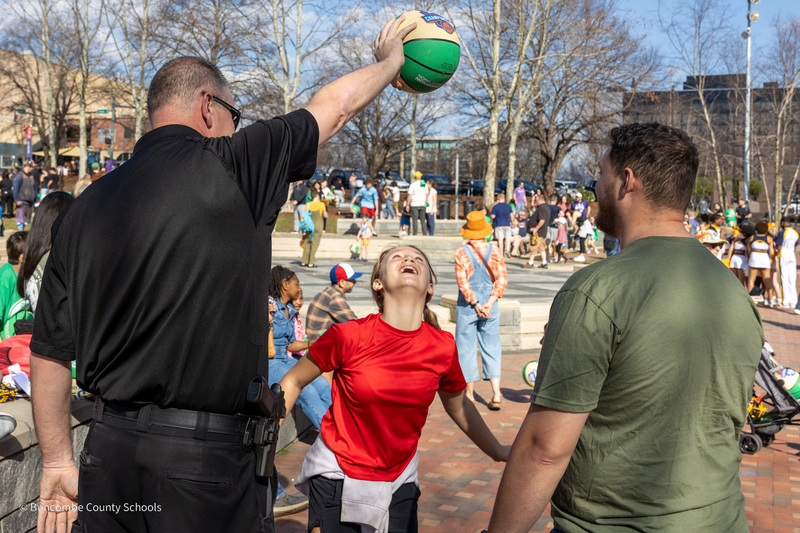 A student looks up at a basketball being held by a deputy.