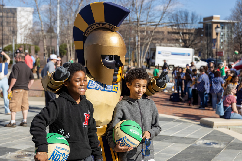 Two students pose with the UNCG Spartan mascot.