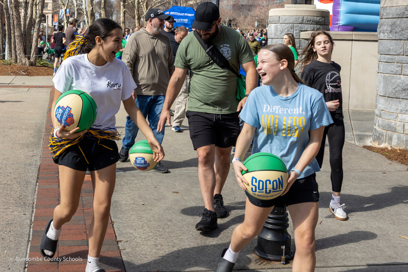 Two students smile as they walk and bounce basketballs in the Downtown Dribble.