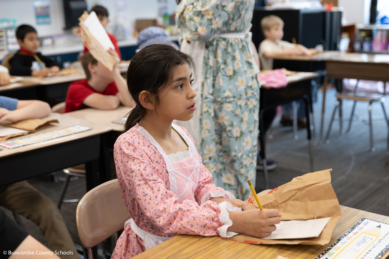 Student writing in a homemade journal. 