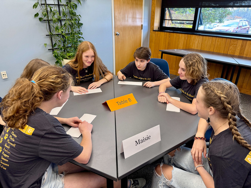Students discuss their answer to a question as they sit around a table.