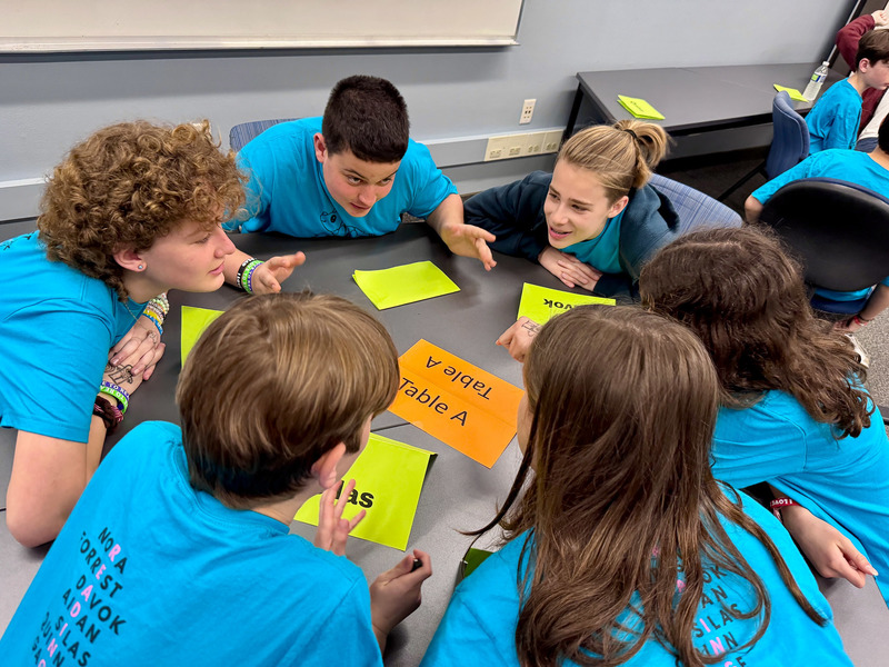 Students discuss their answer to a question as they sit around a table.