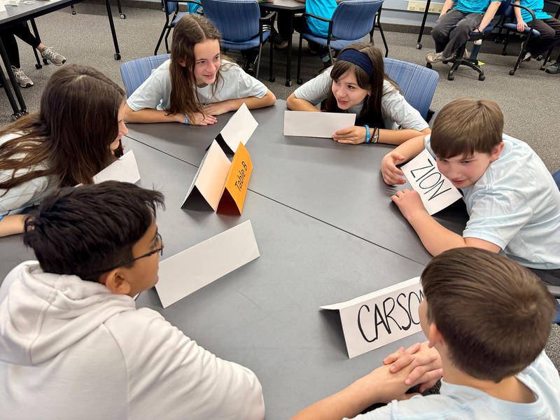 Students discuss their answer to a question as they sit around a table.