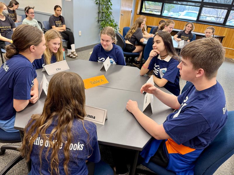 Students discuss their answer to a question as they sit around a table.