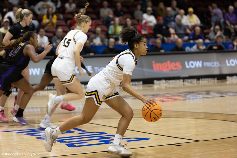 Basketball player dribbling down the court.