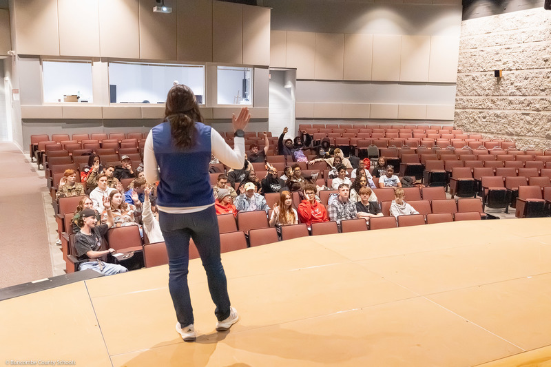 Marisa Romeo speaks from the stage to a group of students who are sitting in the audience.