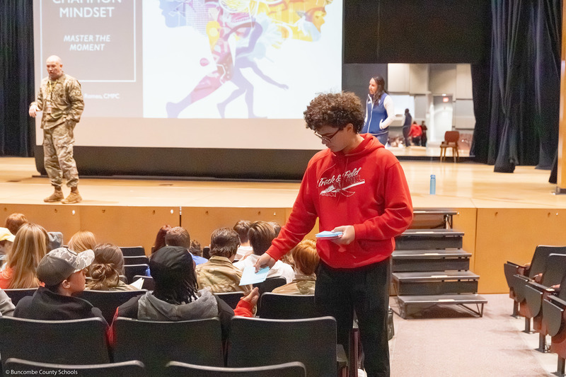 A student hands paper to another student.