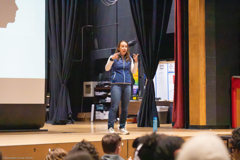 Marisa Romeo speaks on stage with a presentation slide behind her.