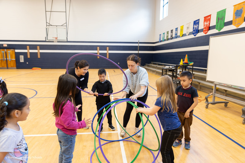 parents and students building a hula hoop hut