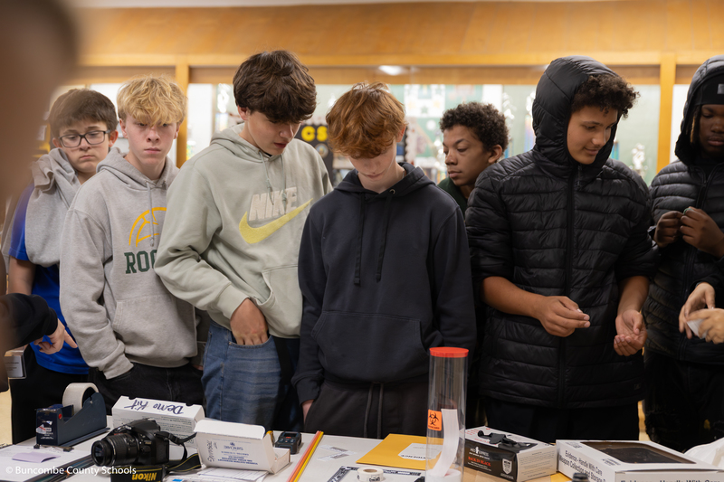 Students looking at items on a table that investigators use when they go to a crime scene.