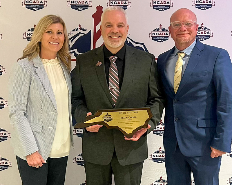 Mr. Carver stands between his principal and an NCADA official. He is holding his award.
