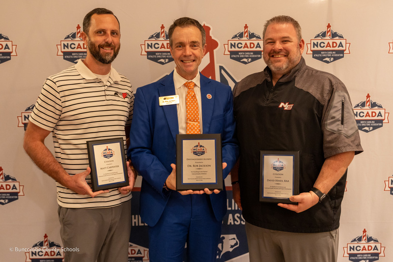 Mr. Carpenter, Dr. Jackson, and Mr. Hines pose in front of the NCADA banner wall holding their plaques.