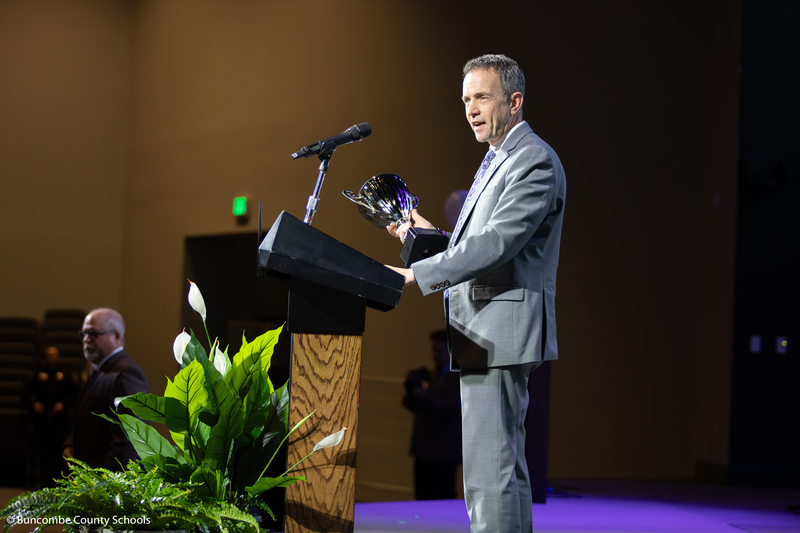 Dr. Jackson speaks at a podium holding the Teacher of the Year trophy.