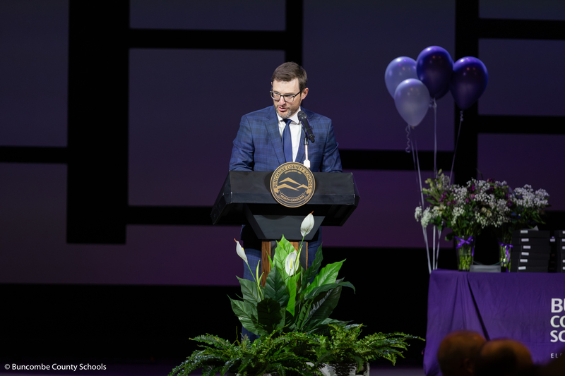 Jason Boyer stands at a podium speaking into a microphone.